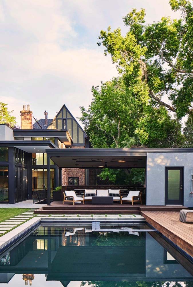 Casa americana moderna com modelo de ed´cula planejada com sofá e poltronas na área da piscina com deck.