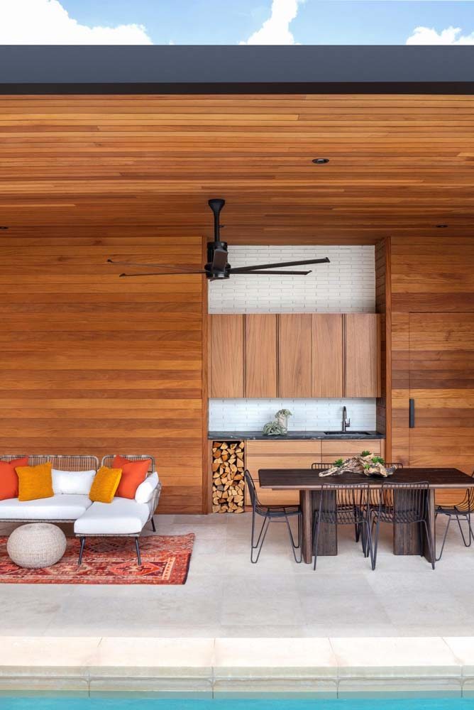 Modelo de edícula com revestimento de madeira da parede ao teto com bancada de cozinha compacta em conjunto com armário planejado.
