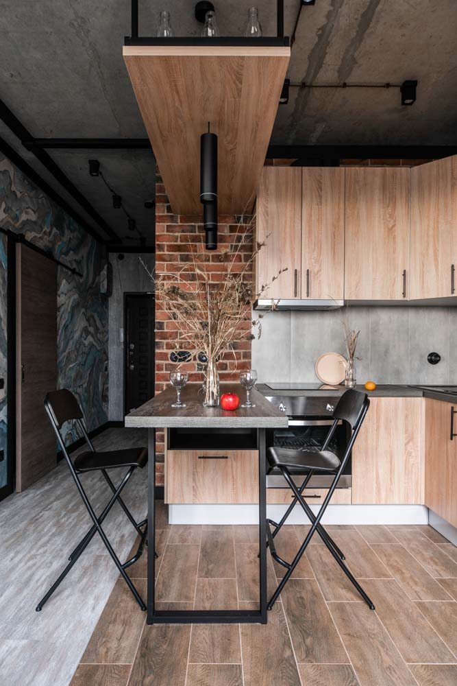 Piso marrom e cozinha compacta com armário planejado de madeira.
