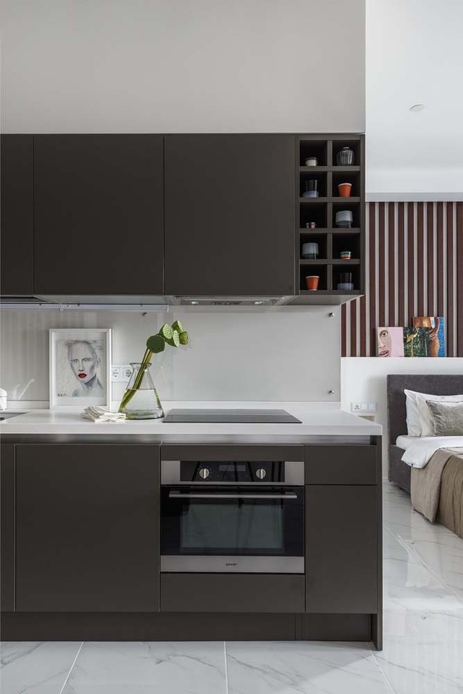 Modelo de cozinha compacta para apartamento pequeno onde os armários receberam a cor marrom escura e a bancada pedra é branca.