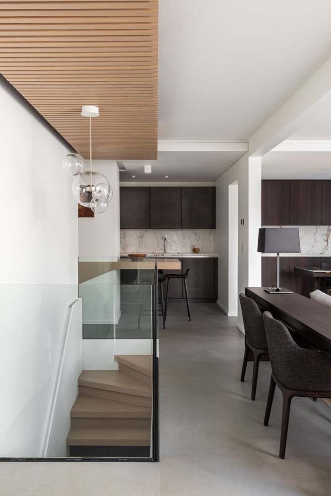 Modelo de cozinha planejada minimalista com armários na cor marrom e bancada com pedra clara.