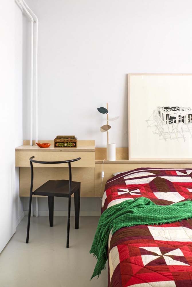 Neste quarto de solteiro com pintura branca, há ainda um móvel planejado na cor madeira clara com cabeceira e escrivaninha unidas.