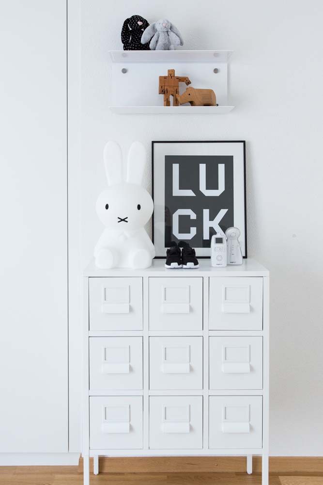 Uma cômoda minimalista branca com 9 gavetas para um quarto infantil minimalista.