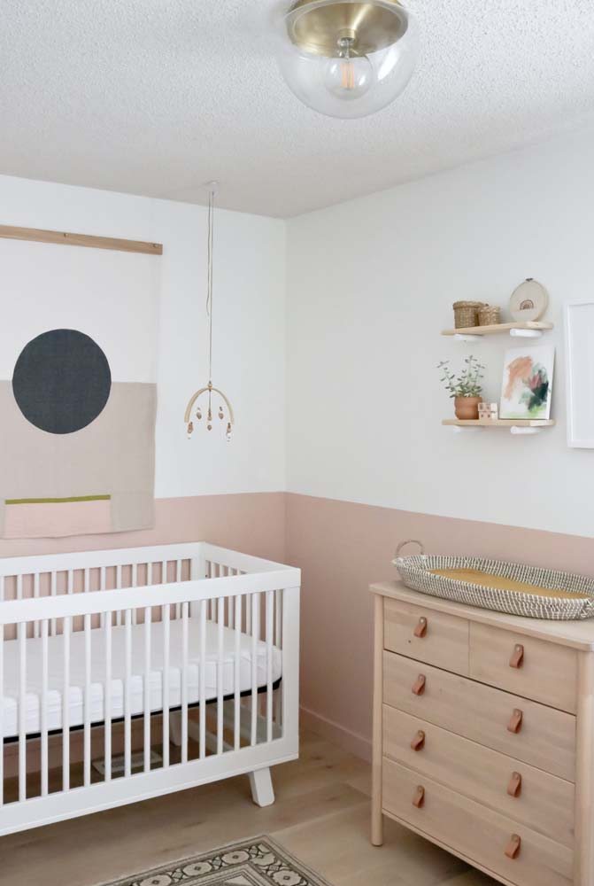Decoração de quarto infantil simples e combinação de branco e madeira no berço e na cômoda infantil.