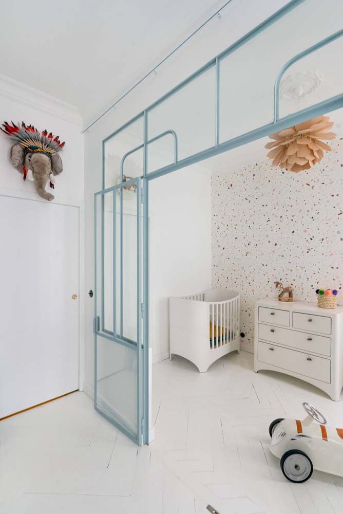 Quarto infantil moderno, com revestimento em granilite na parede e cômoda branca.