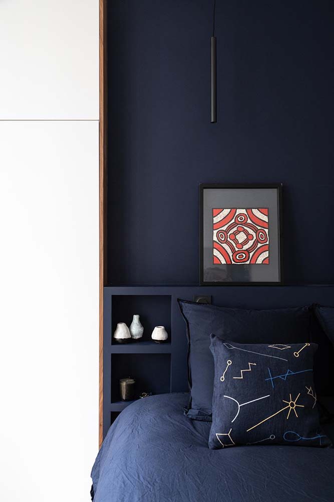 Azul marinho como uma cor calmante para a mente, seguindo a mesma paleta da cama até a cabeceira e parede com pintura.