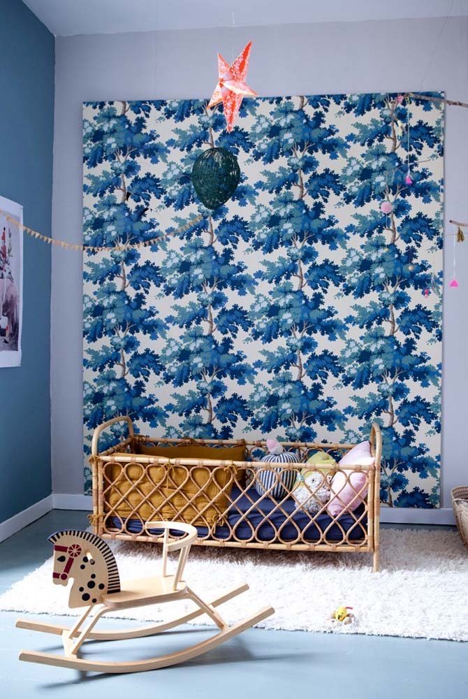 Combinação de pintura azul com papel de parede que também leva a cor no quarto infantil.