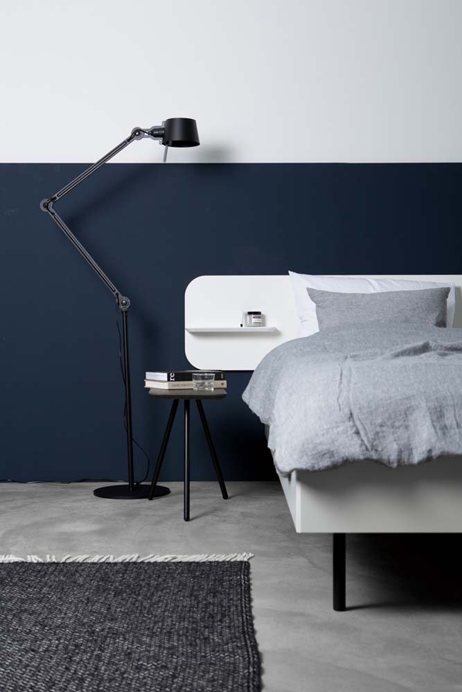 Já este quarto minimalista de casal conta com meia parede pintada na cor azul marinho e a outra metade na cor branca.