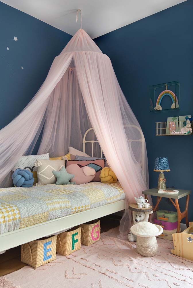 Modelo de quarto de bebê com pintura azul marinho na parede e lindo dossel rosa claro.