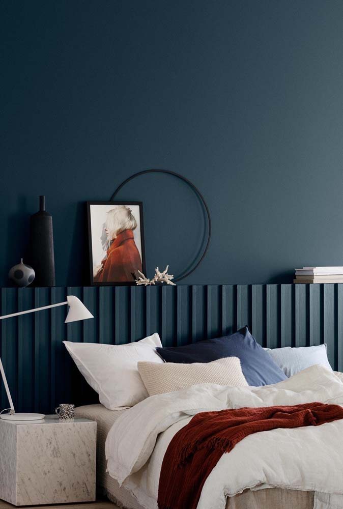 Sinta a tranquilidade do azul profundo em contraste com a roupa de cama clara da cama de casal.