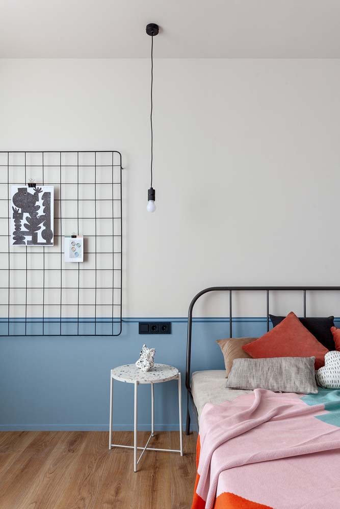 Já neste quarto de casal minimalista, apenas uma faixa inferior da parede recebeu a pintura com a cor azul claro.