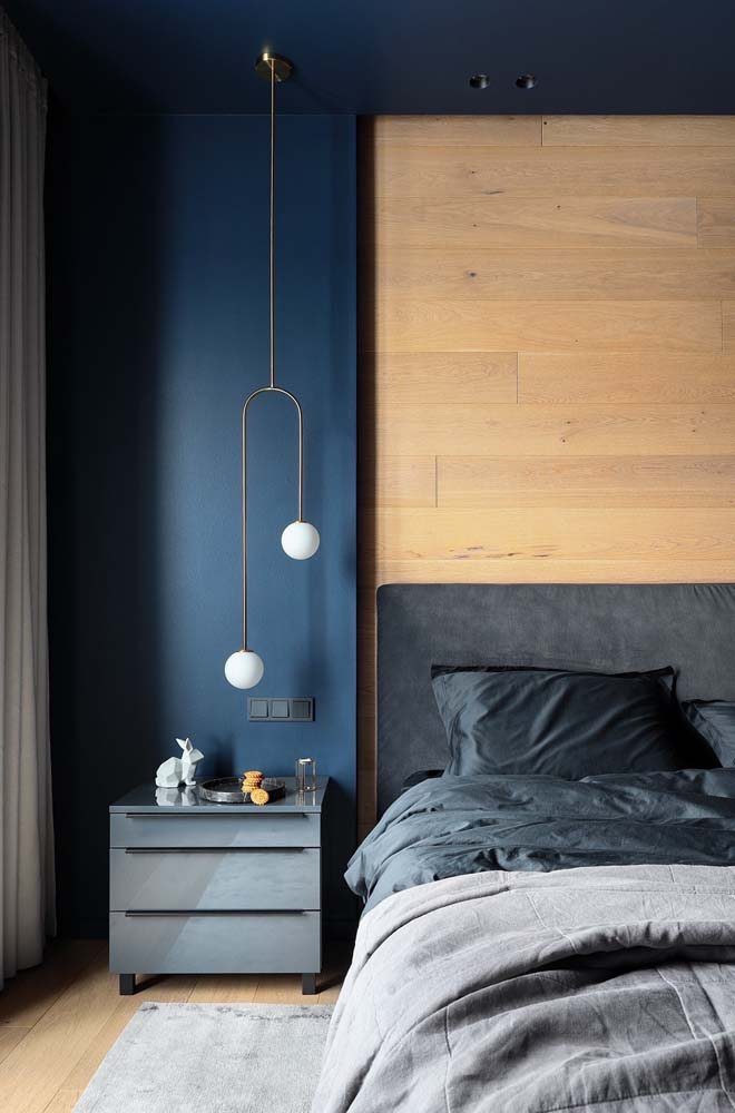 O azul se destaca neste quarto em contraste com a parede em madeira clara.