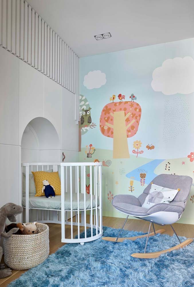 Projeto moderno de quarto infantil com berço, papel de parede com azul claro e tapete felpudo azul.
