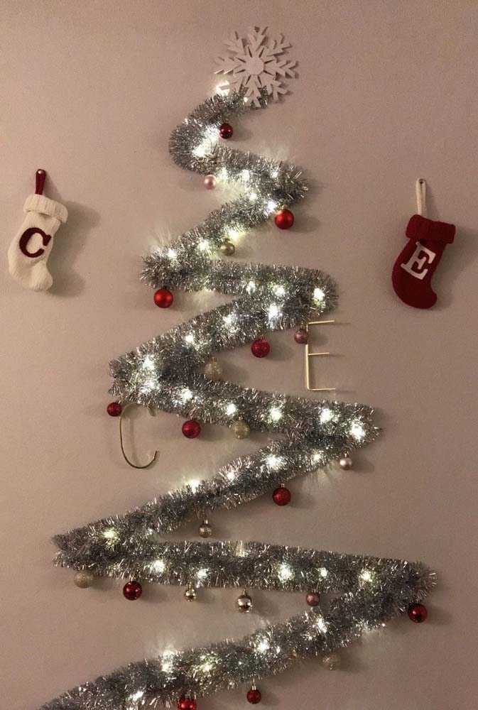 Árvore de Natal de parede simples: uma guirlanda, um pisca pica e enfeites variados.