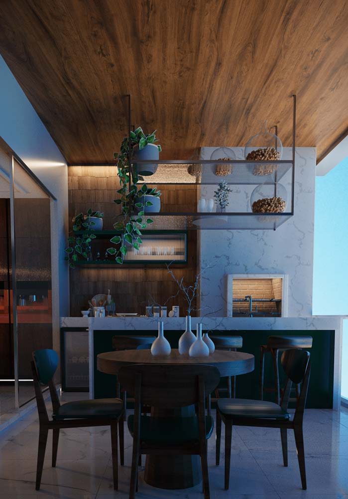 A churrasqueira de alvenaria ganhou iluminação própria nesse projeto de área gourmet rústica de apartamento.