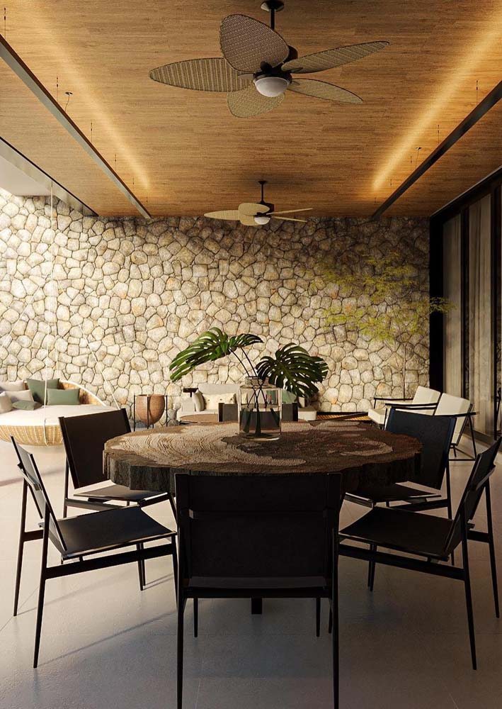 A parede de pedra deixa o ambiente mais elegante, perfeito para uma área gourmet rústica aberta.