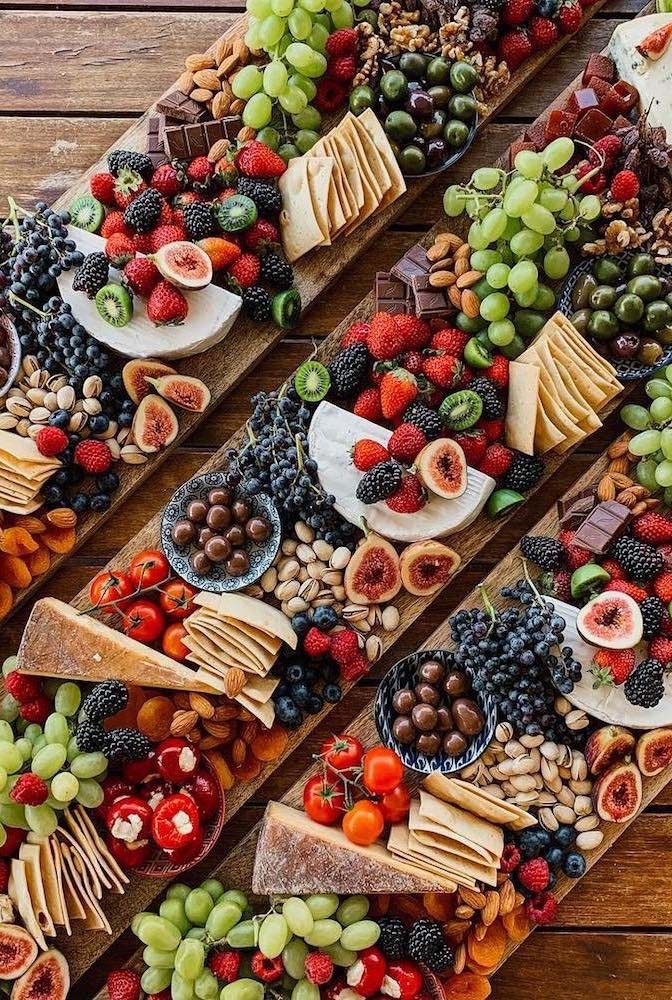 Uma tábua comprida de frutas, doces e queijos.